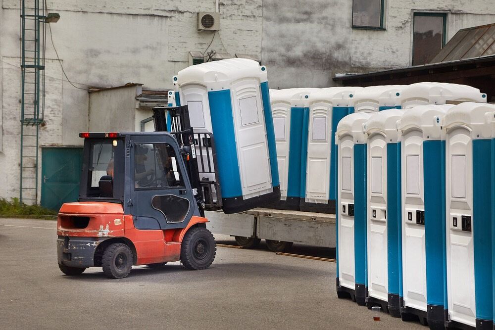 A Forklift is Unloading Portable Toilets— Coffs Coast and Country Temp Fence in Sapphire Beach, NSW