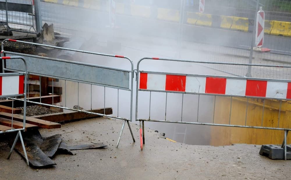 A Red and White Barrier is Surrounding a Hole in the Ground — Coffs Coast and Country Temp Fence in Sapphire Beach, NSW