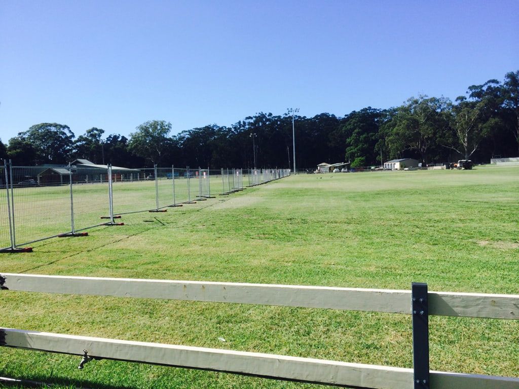 A large grassy field with a white fence in the foreground — Coffs Coast and Country Temp Fence in Sapphire Beach, NSW