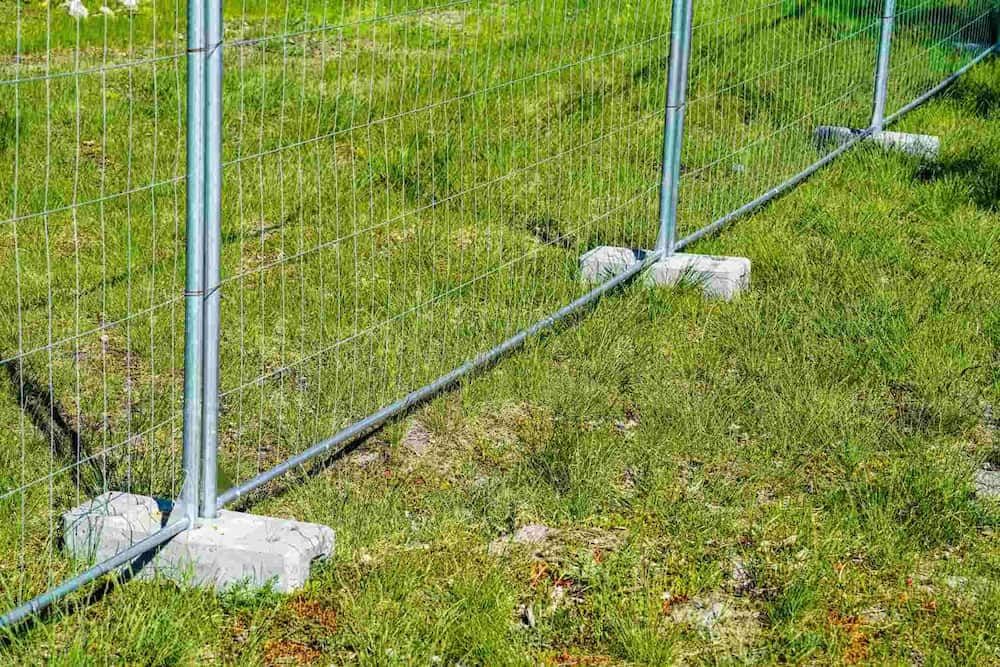 A Temporary Metal Fence is Sitting on Top of a Lush Green Field — Coffs Coast and Country Temp Fence in Sapphire Beach, NSW