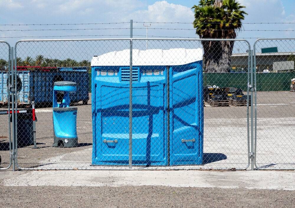 A Blue Portable Toilet is Behind a Temporary Gate Fence — Coffs Coast and Country Temp Fence in Sapphire Beach, NSW