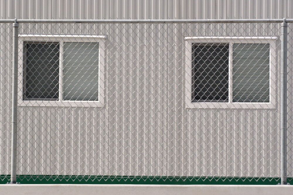 A Temporary Fence is Surrounding a Building With Two Windows — Coffs Coast and Country Temp Fence in Sapphire Beach, NSW