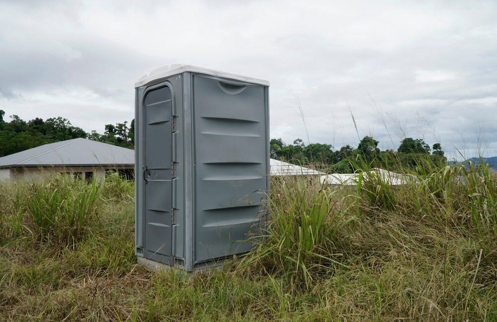 A Portable Toilet is Sitting in the Middle of a Field — Coffs Coast and Country Temp Fence in Sapphire Beach, NSW