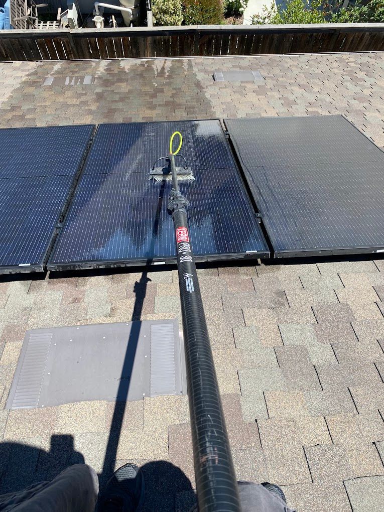 A person is cleaning a solar panel on a roof.