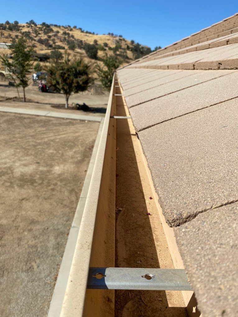 A wooden gutter is attached to the side of a roof.