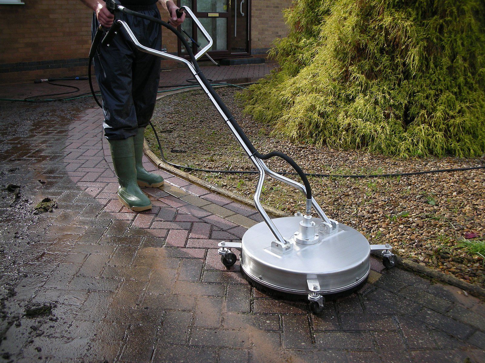A man is standing on top of a roof cleaning a tree.