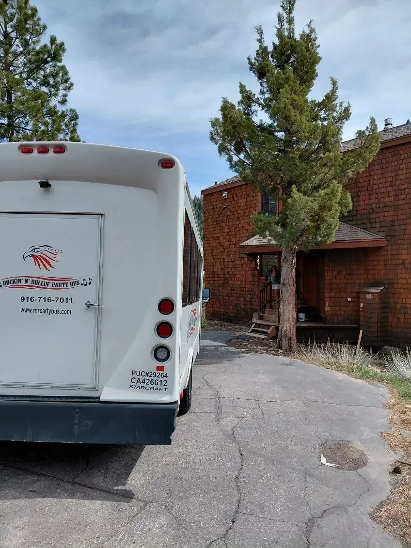 White RV parked by a cracked driveway beside a red brick house and trees