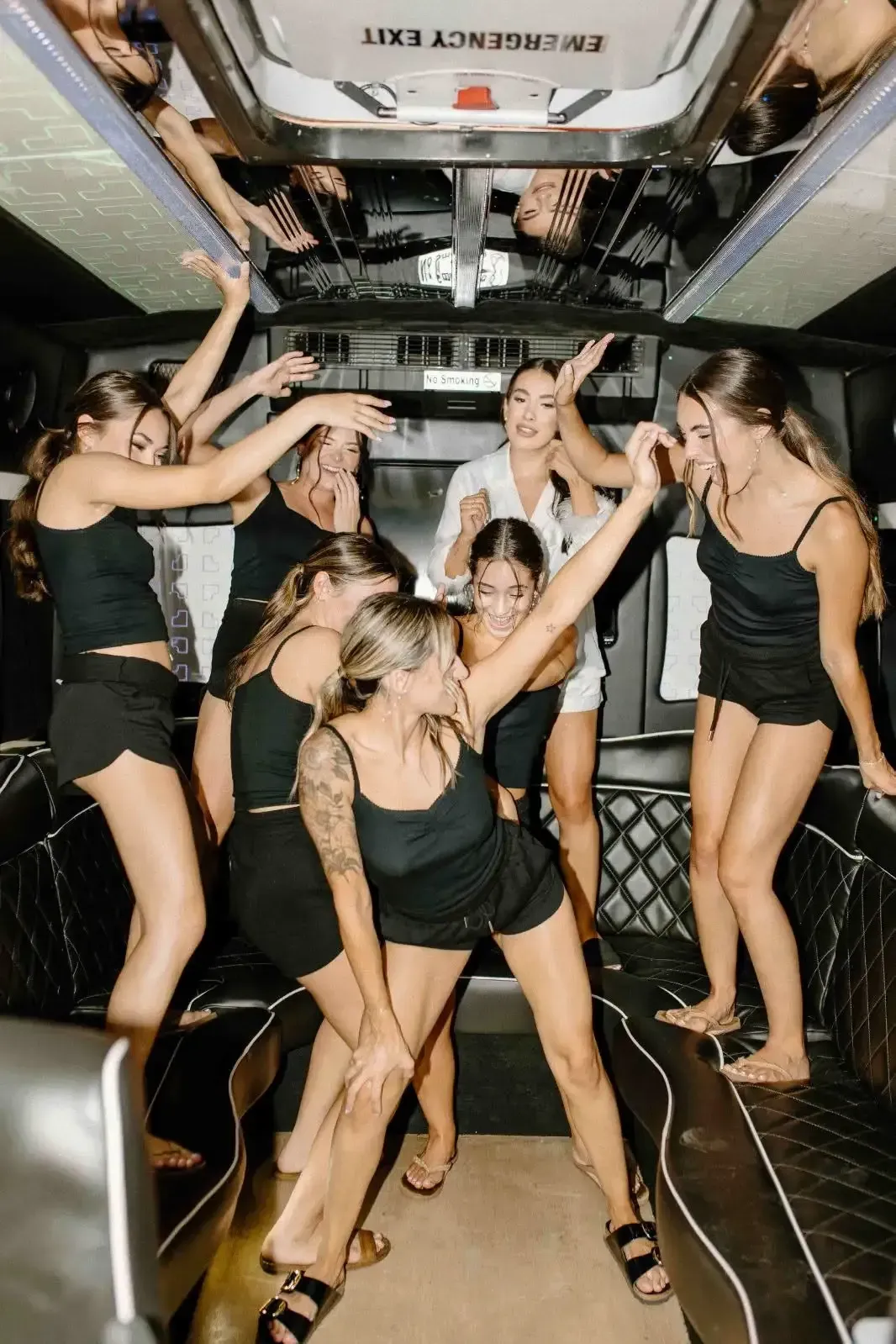People dancing in black dresses inside a decorated party bus