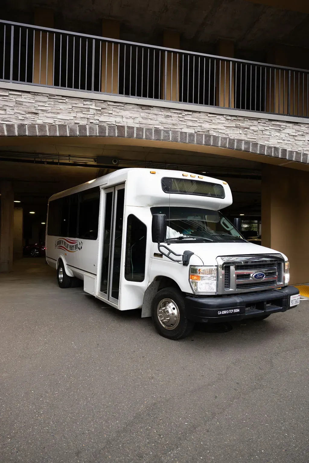 White shuttle van parked outside a building entrance under an overhang.