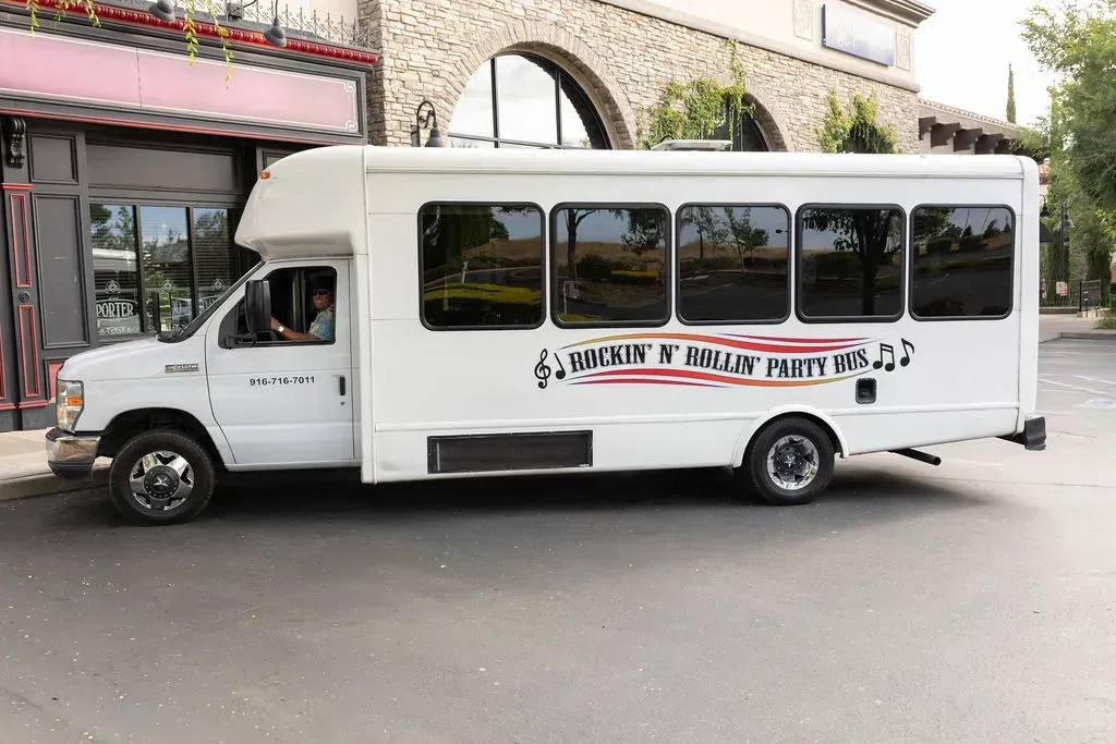 White shuttle bus parked on a street beside a building