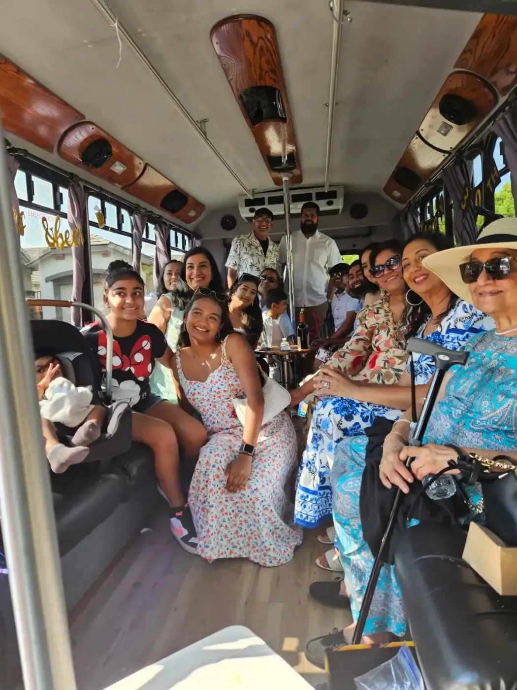 Group of people smiling and sitting inside a decorated shuttle bus with large windows