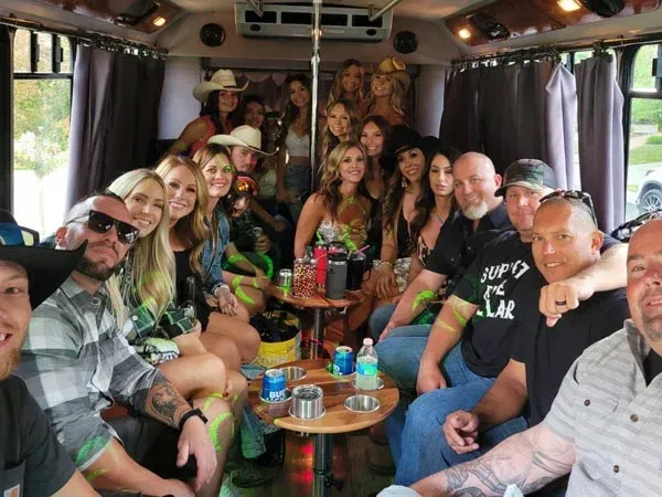 People dancing inside a party bus with colorful lights and smiles.