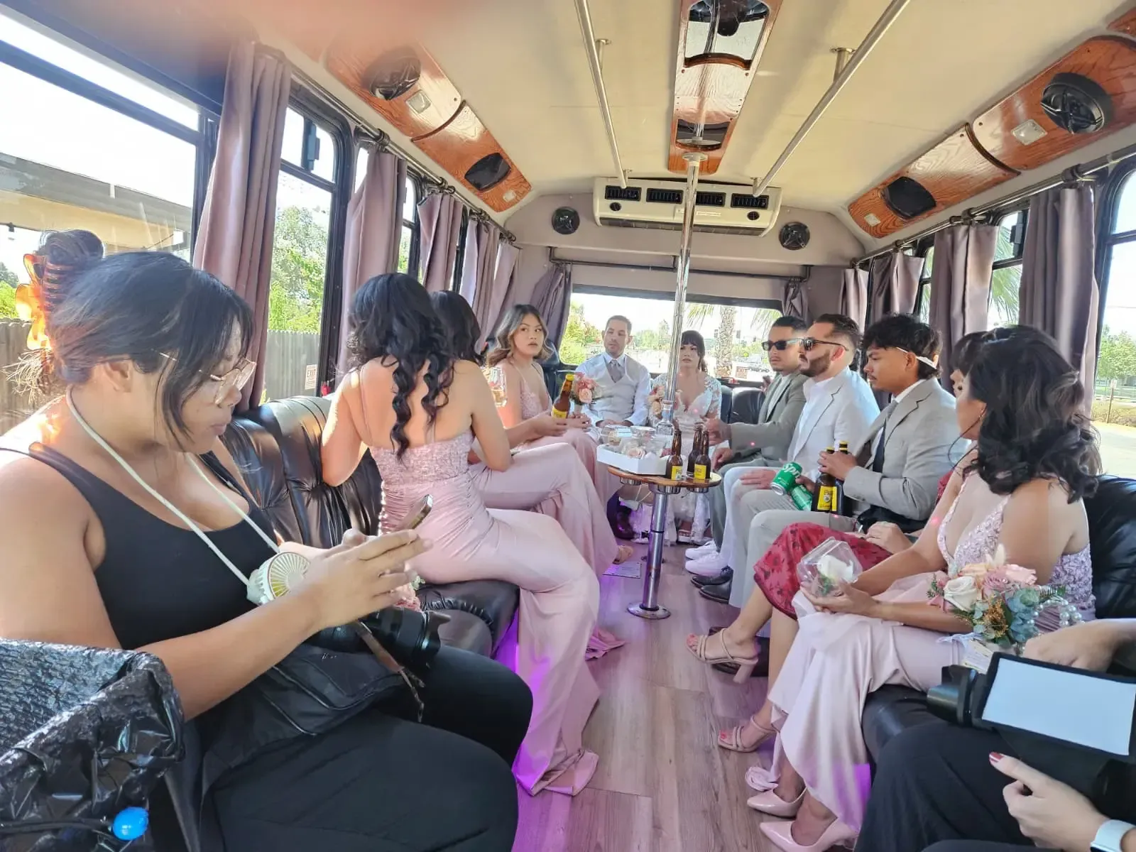 Passengers seated inside a vintage bus, chatting and holding phones, with pastel outfits and floral decor.