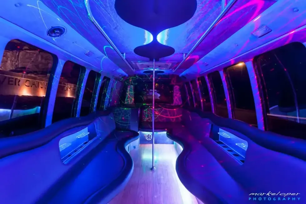 Empty neon-lit bus interior with blue and purple ambient lighting and curved seats