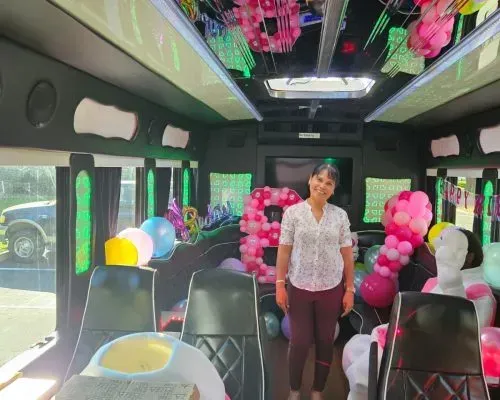 Decorated bus interior with pink balloons and a person standing in the aisle