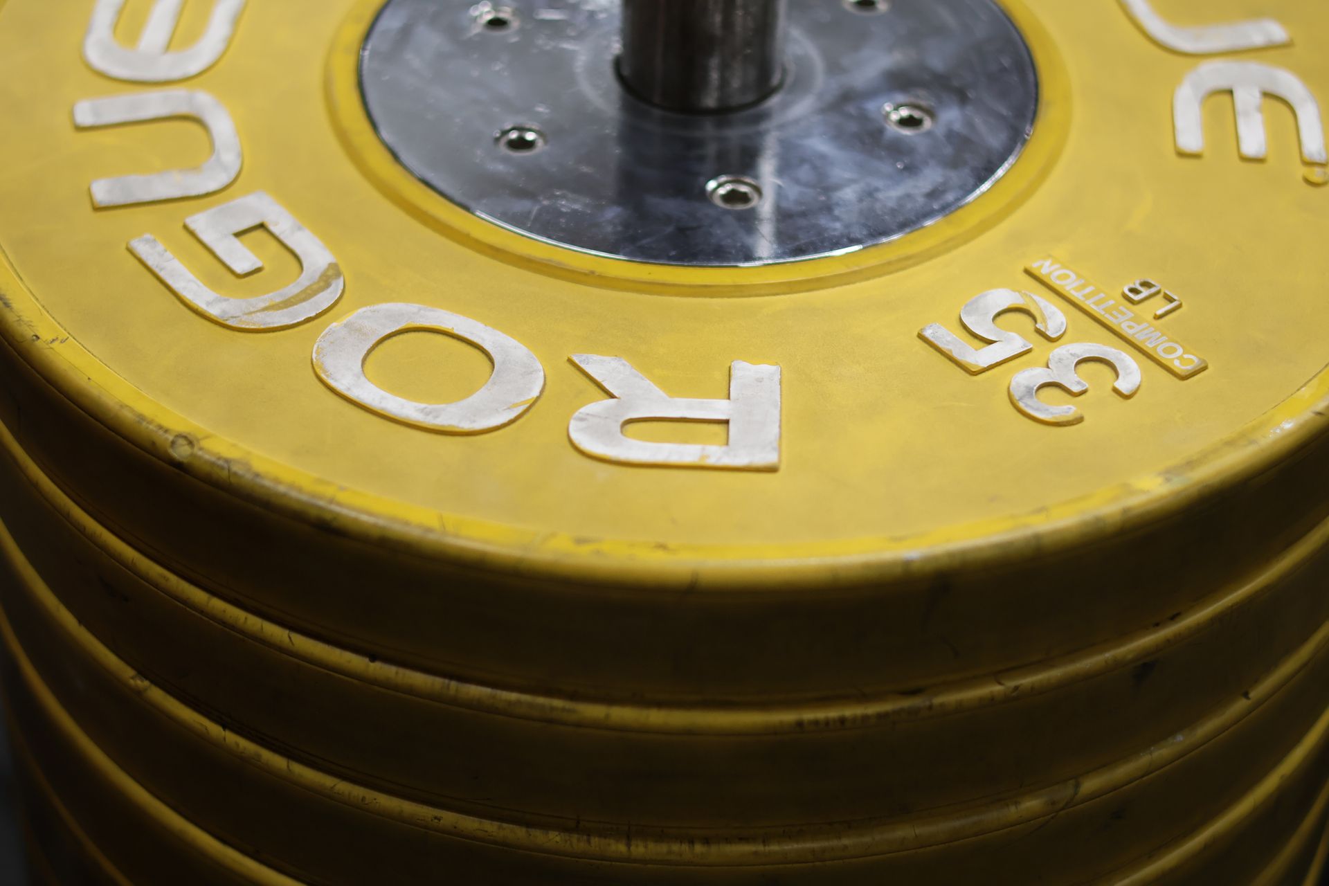 Close-up of yellow Rogue 35-pound weight plate on a barbell sleeve