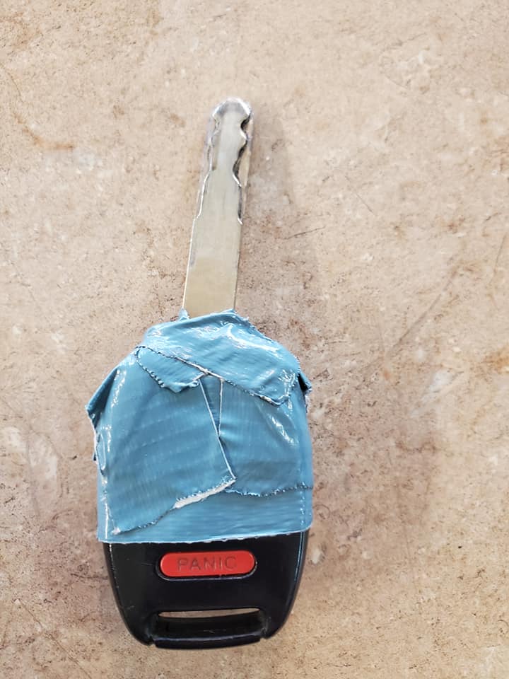 Car key with a teal covering; on a beige surface.