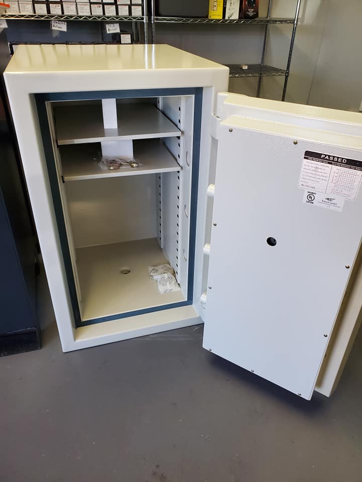 Open white safe with shelves and ajar door, inside a store.