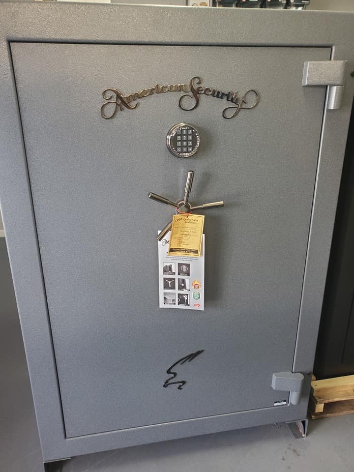 Gray American Security safe with digital keypad, spoke handle, and decorative script.