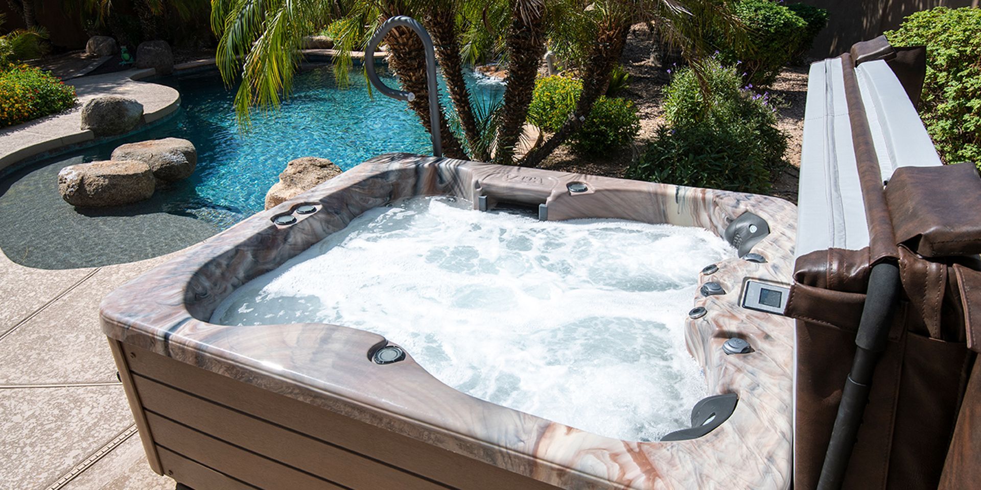 Hot tub with jets, next to a pool in a landscaped yard.