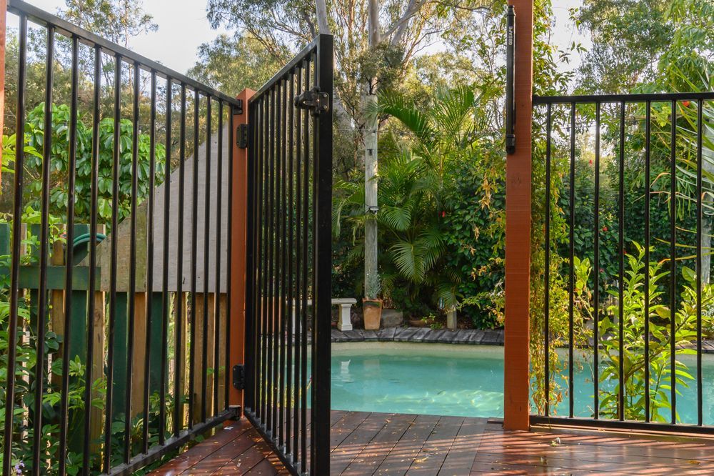A Black Metal Pool Gate Stands Open on a Wooden Deck — Get My Pool Certified in Coolangatta, QLD