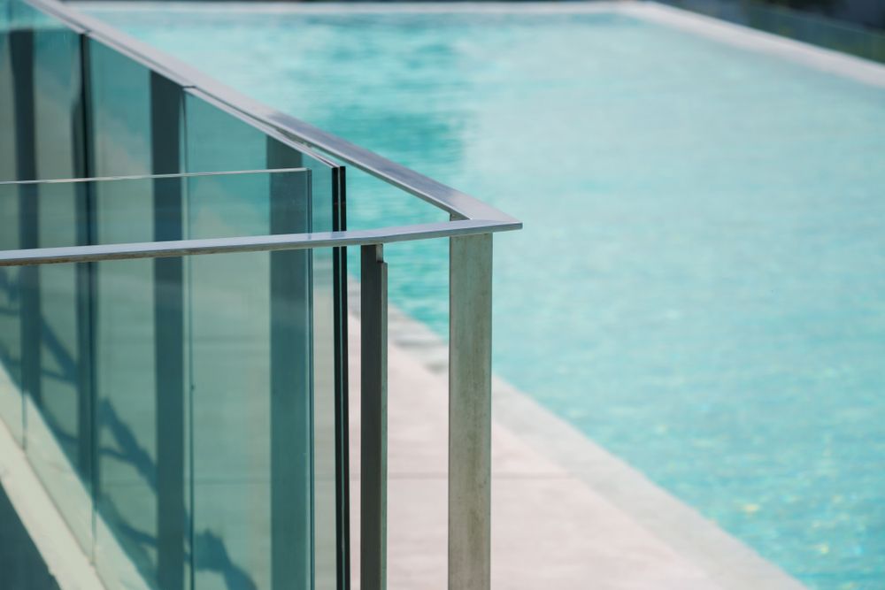 A Metal and Glass Railing Borders a Clear Blue Swimming Pool — Get My Pool Certified in Palm Beach, QLD