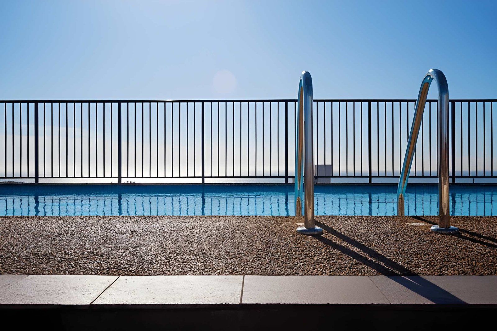 A Swimming Pool at Eye Level With a Metal Ladder — Get My Pool Certified in Burleigh Heads, QLD