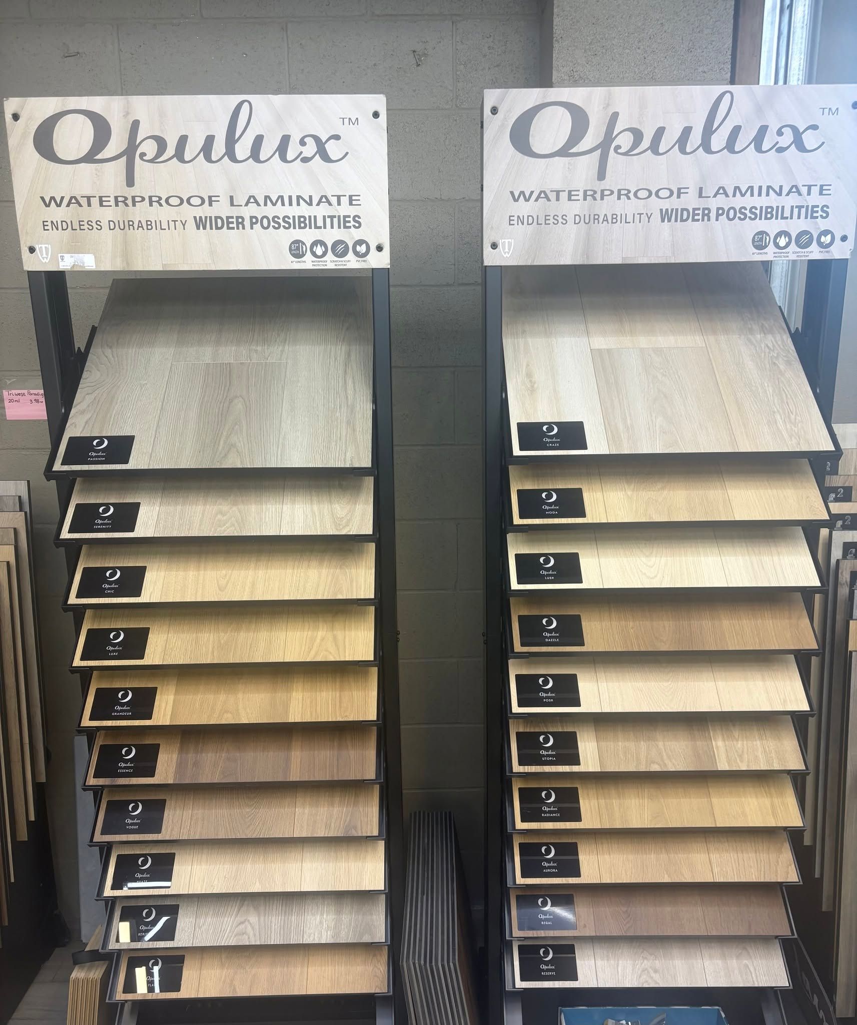 Two display racks of Opulux laminate samples in a store, with light and dark wood finishes.