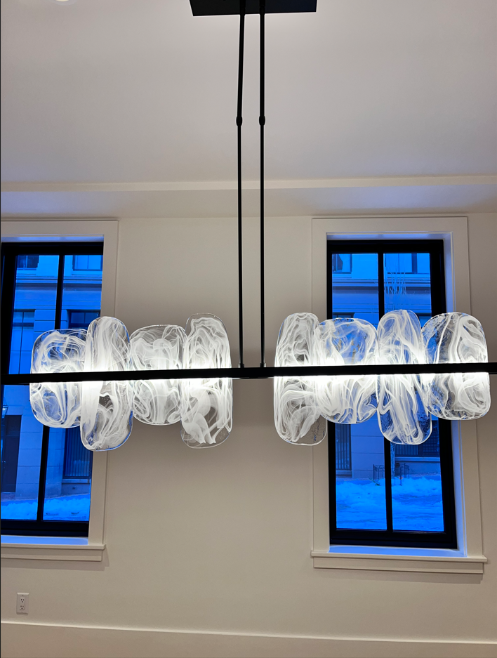 A chandelier is hanging from the ceiling in a room with two windows.