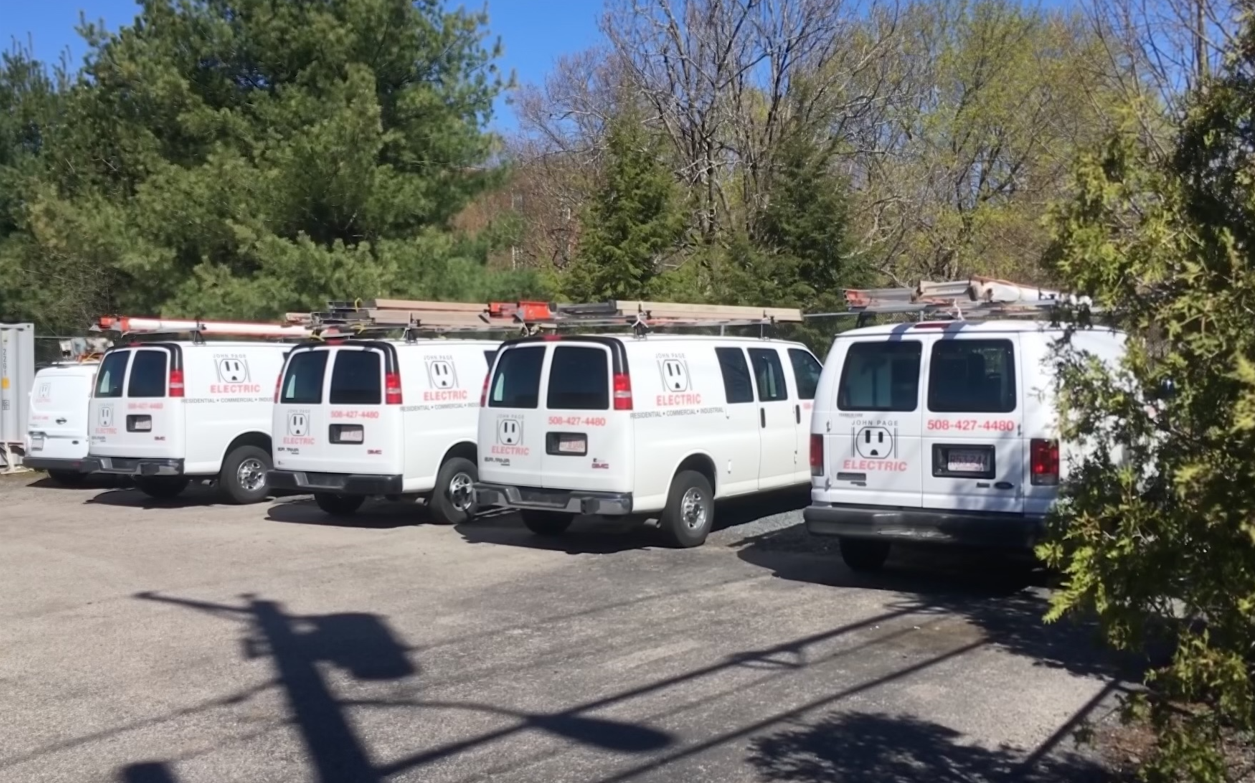A row of white vans are parked in a parking lot.