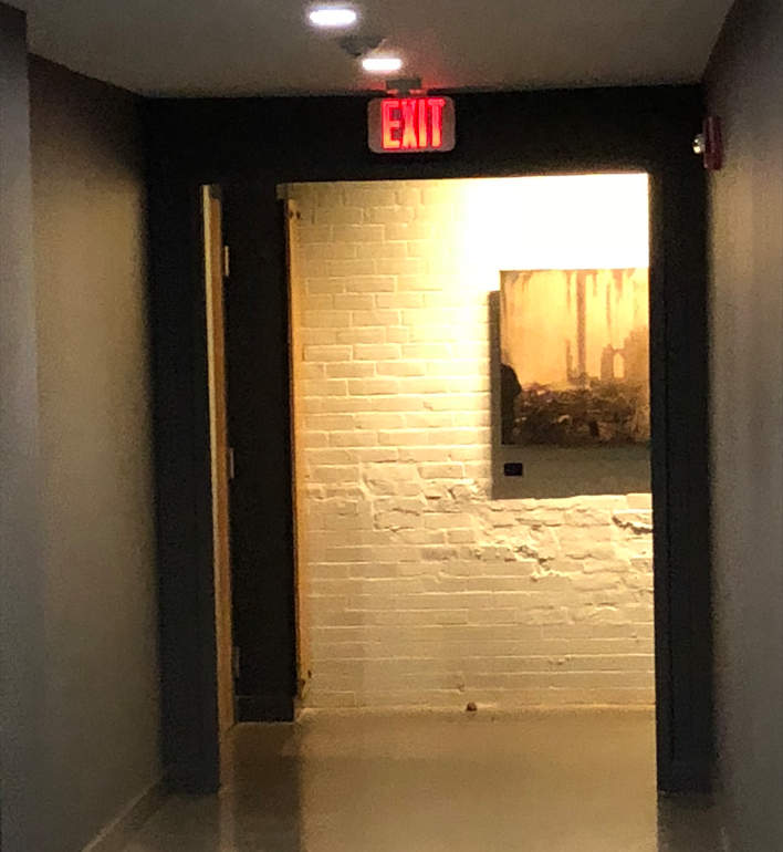 A hallway with a red exit sign above it