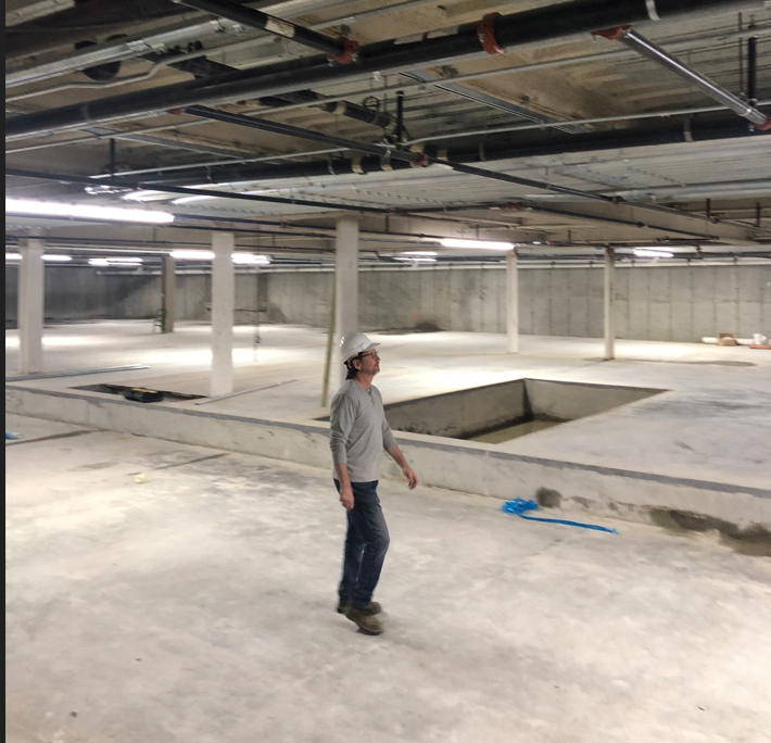 A man wearing a hard hat is standing in an empty building