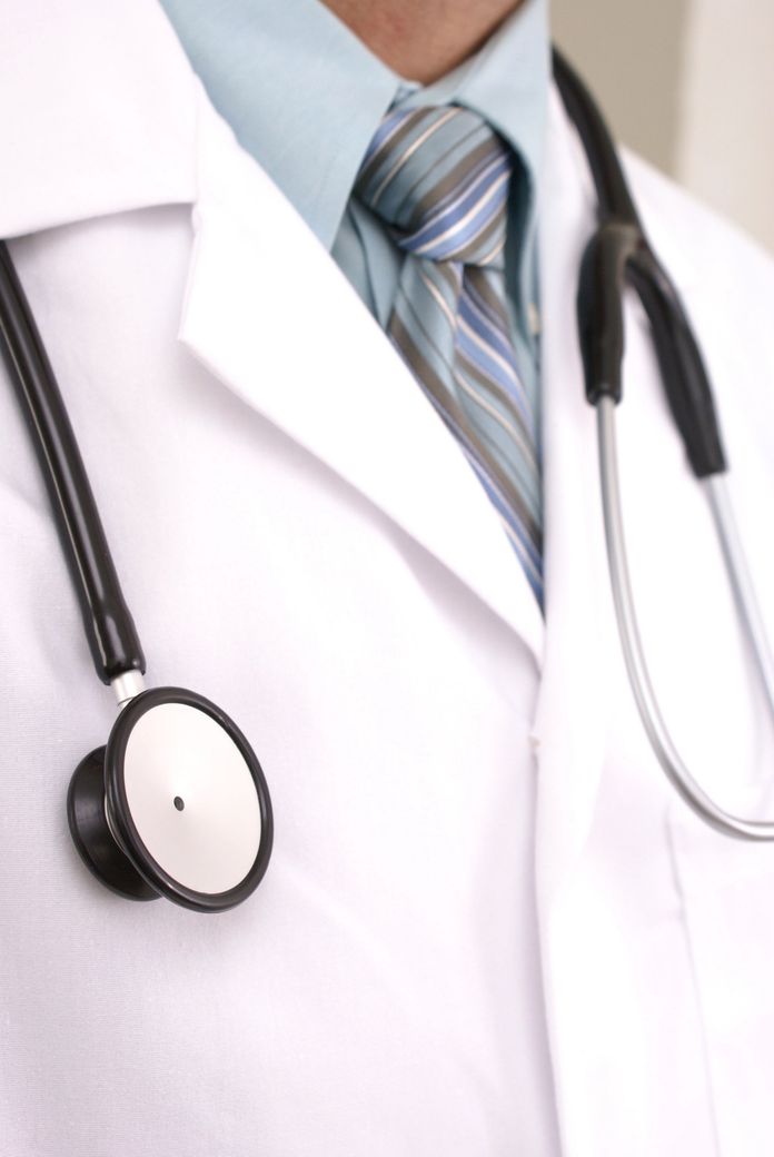 Médico con bata blanca, estetoscopio negro y corbata a rayas.