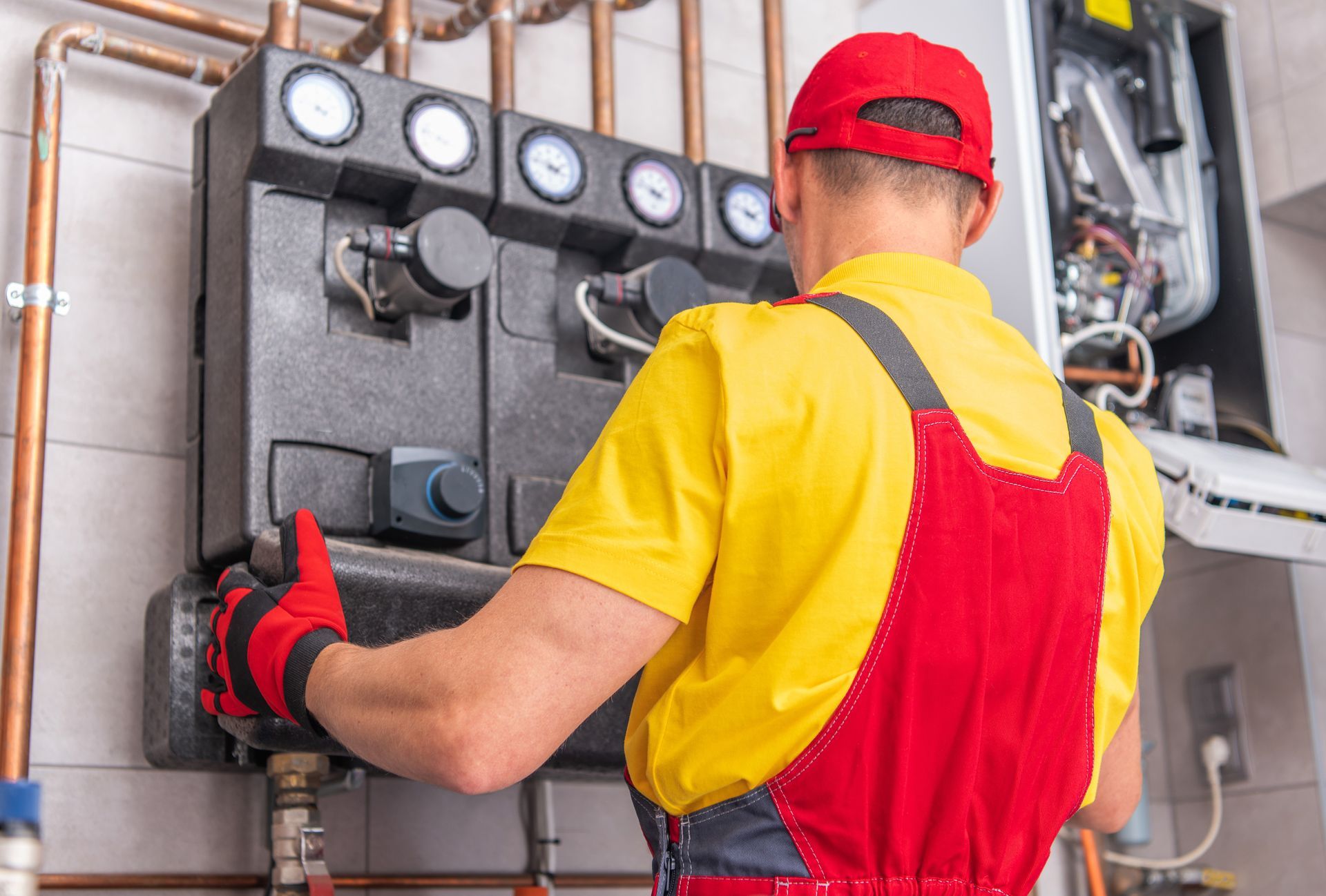 Commercial plumber adjusting valves on a boiler system with pressure gauges