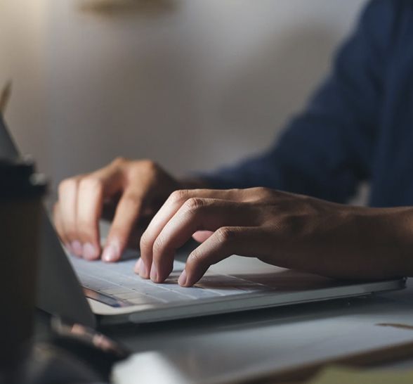 Person typing on a laptop with hands visible, close-up. Focus on the hands and keyboard.