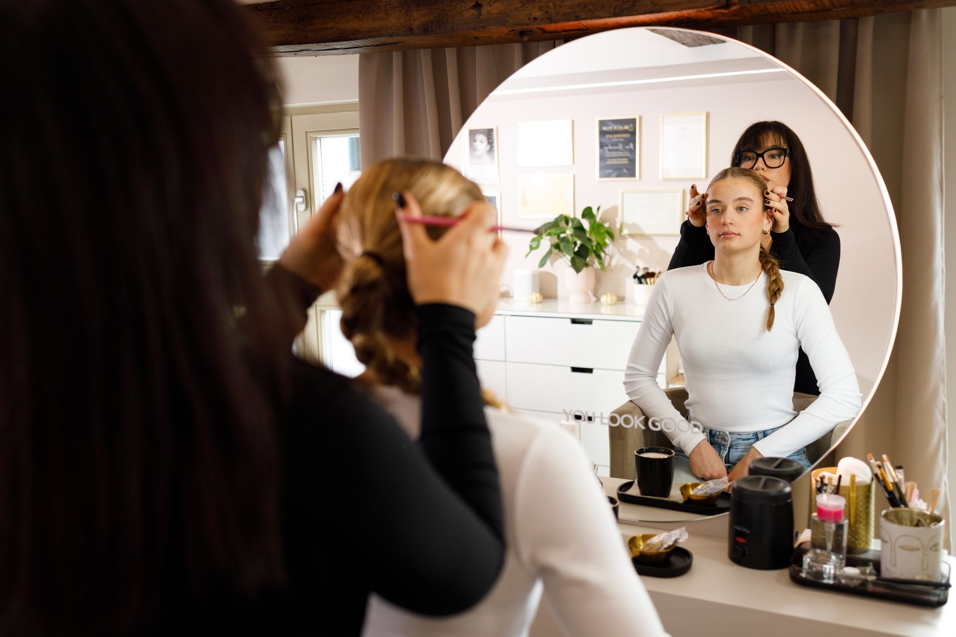 Eine Frau lässt sich vor einem Spiegel die Haare frisieren.