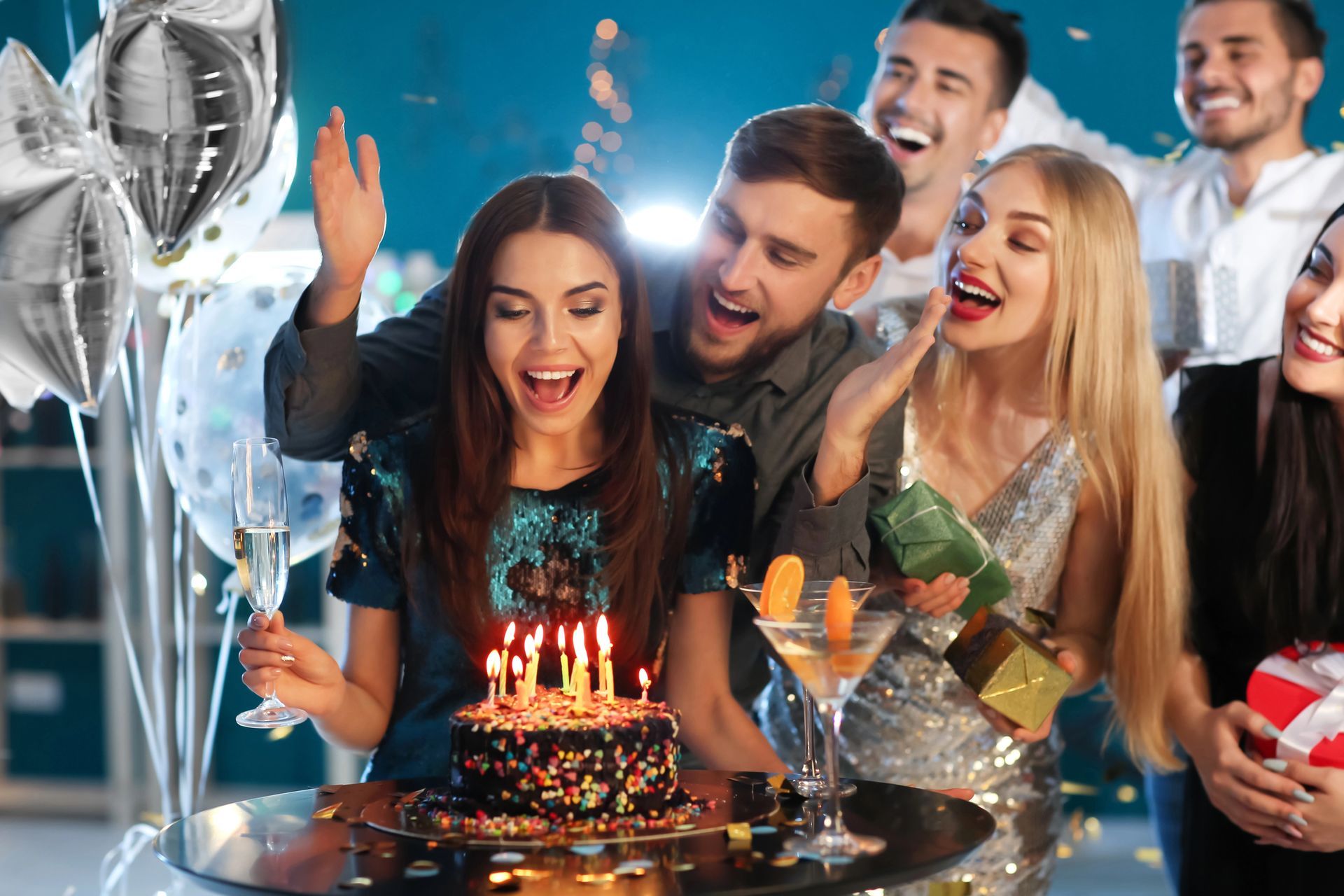Amici che festeggiano un compleanno con torta, candeline, palloncini e champagne a una festa
