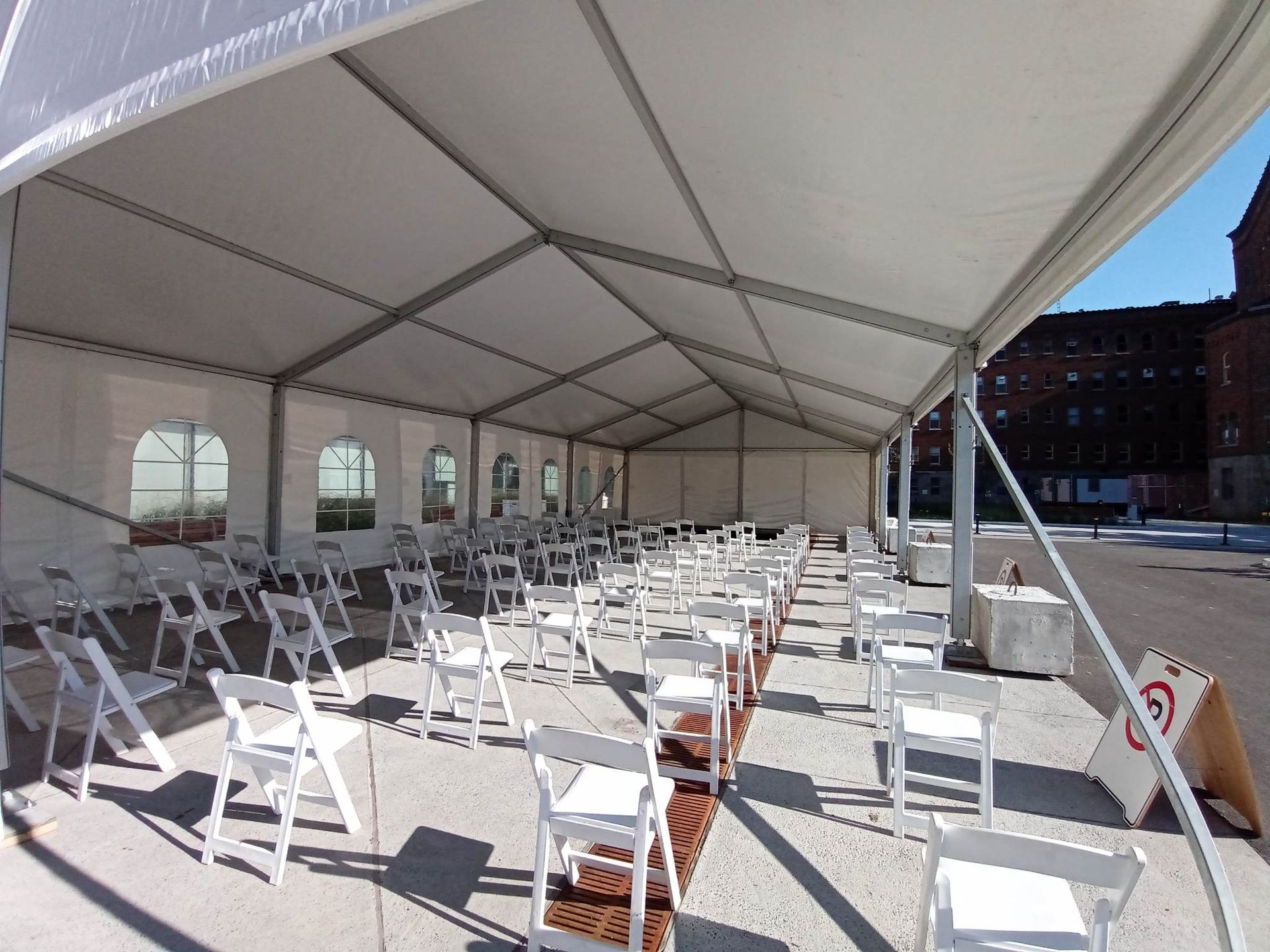 Une grande tente blanche avec des chaises pliantes blanches en dessous
