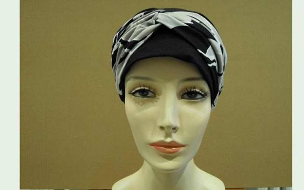 Testa di manichino che indossa un turbante con motivi bianchi e neri.