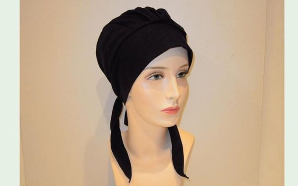 Foulard nero su una testa di manichino con lunghi lacci pendenti.