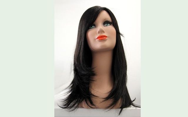 Parrucca nera su testa di manichino con lunghi capelli scalati, su sfondo bianco.