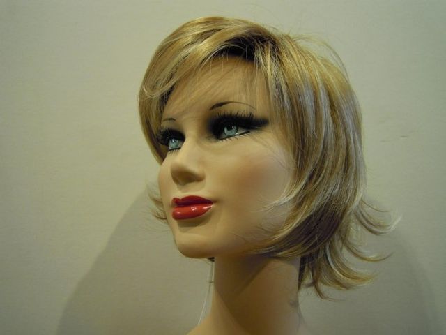 Testa di manichino con capelli biondi corti, occhi azzurri e rossetto rosso.