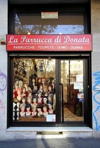 La vetrina di un negozio di parrucche con un'insegna rossa: