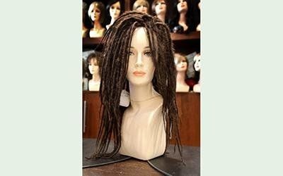 Testa di manichino con parrucca castana con dreadlock esposta in un negozio.