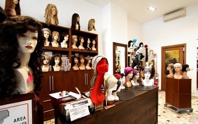 All'interno di un negozio di parrucche, con parrucche esposte su manichini di vari stili.