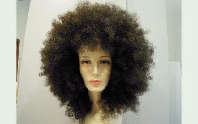Testa di manichino con grande parrucca afro castana.