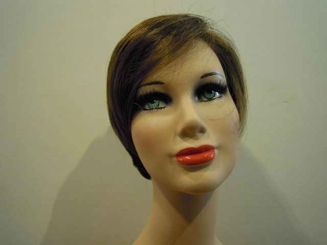 Testa di manichino con capelli castani, occhi azzurri e labbra rosse.