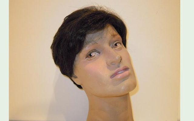 Testa di manichino con capelli corti e scuri, pelle chiara, sguardo leggermente rivolto verso l'alto.