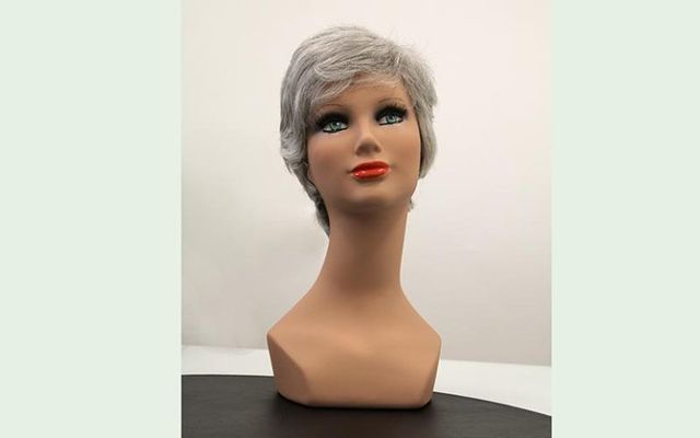 Testa di manichino con parrucca corta e grigia e rossetto rosso brillante.