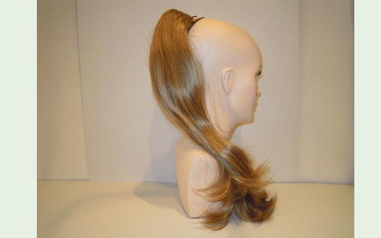 Testa di manichino con estensione di capelli biondi a forma di coda di cavallo.